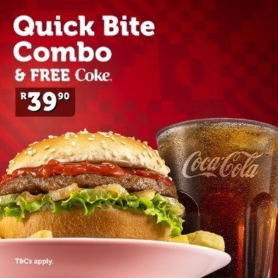 Burger and chips on a white plate next to a glass of Coke.